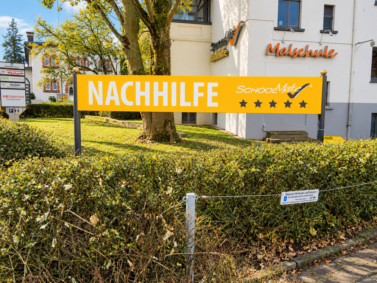 Außenansicht des SchoolMate-Standorts in Bielefeld-Schildesche: gelbes Schild mit der Aufschrift Nachhilfe vor dem Gebäude an der Straße.